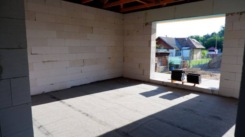 Construction of a family house in Radava with a view of the unfinished walls and the surrounding landscape.