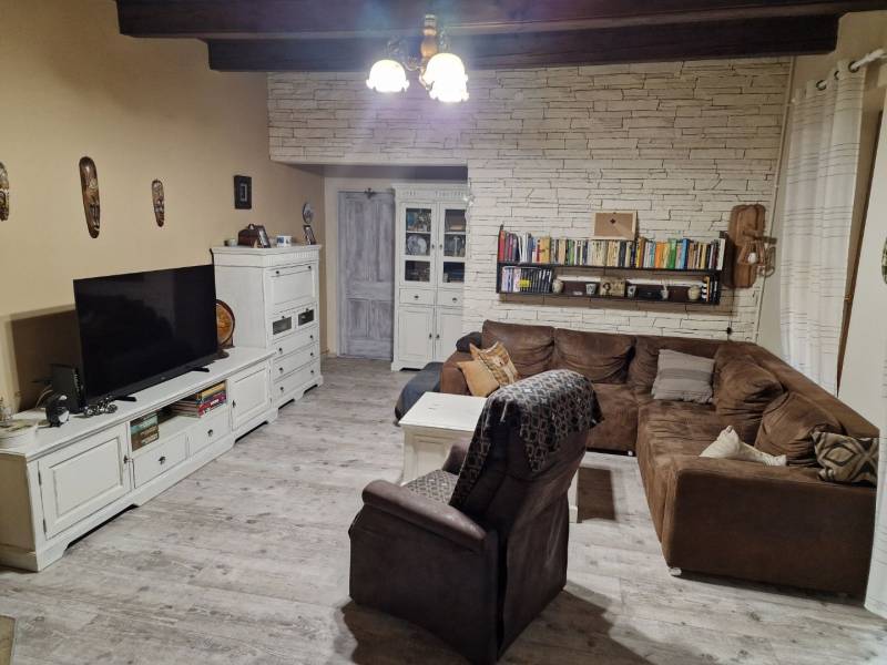 Living room with a corner sofa, white furniture, and a wooden decor floor in a family house.
