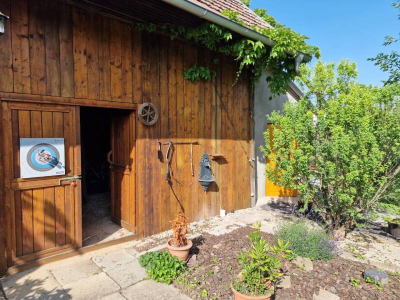 The courtyard of a family house in Dlhá nad Váhom with a wooden wall, greenery, and a target on the door.