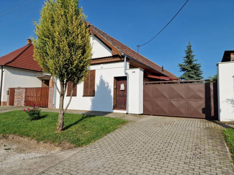 A family house in Dlhá nad Váhom with a gate and a front garden, complemented by trees.