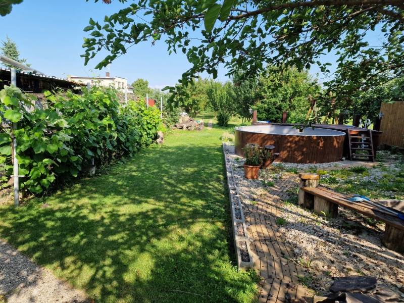 The garden of a family house in Dlhá nad Váhom with a swimming pool, bench, greenery, and a walkway.