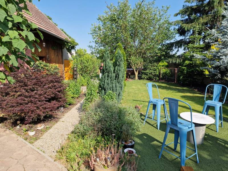 The garden of a family house in Dlhá nad Váhom with a wooden cottage and blue chairs.