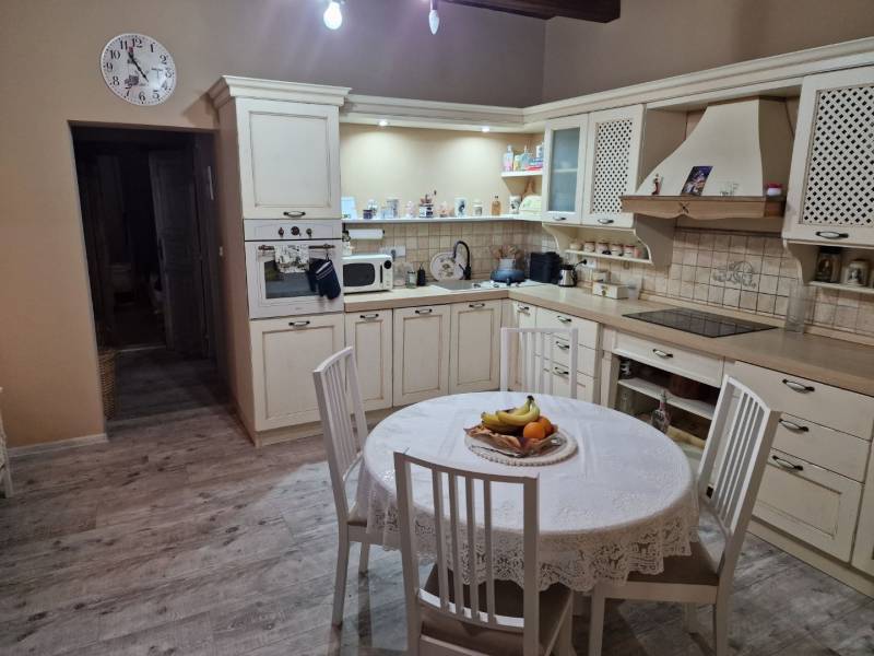 A kitchen in a family house with a wooden decor floor, tiles, and a round table.