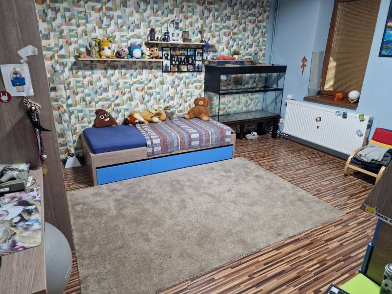 Children's room with a bed, aquarium, toys, and a floor with a wooden decor in a family house.