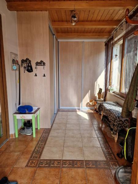 Hallway with tiles, built-in wardrobe, and bench in a family house.