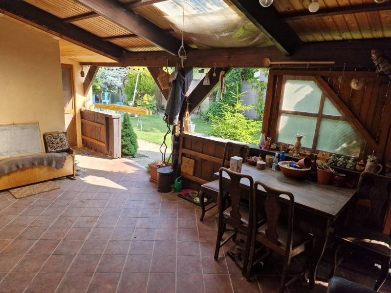 Rustic terrace of a family house with wooden furniture and a view of the garden.