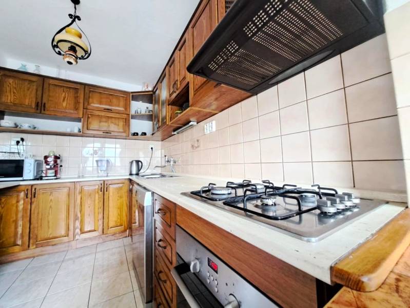 A kitchen in a family house with a gas stove, dark brown cabinets, and ceramic tiles.