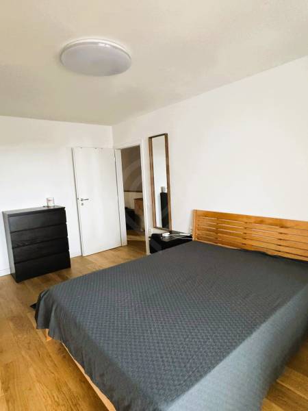 Bedroom in a family house with a bed, dresser, and wooden decor flooring.