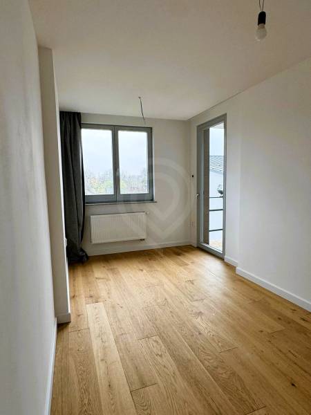 A room in a family house with a wooden decor floor and large windows.