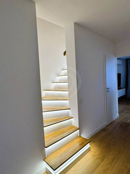 A staircase in a family house with built-in lighting and flooring with a wooden decor.