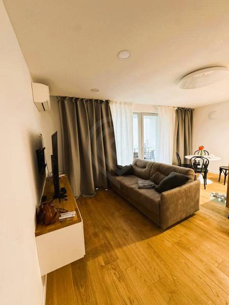 Living room in a family house with a wooden decor floor, gray sofa, and curtains.