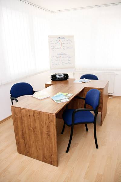 Office with a wooden desk, blue chairs, and a board, commercial premises.
