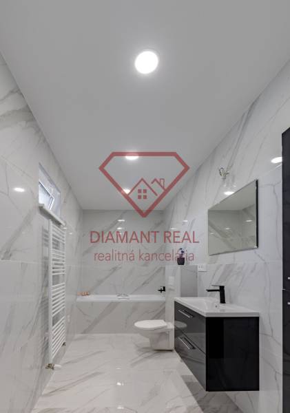 A bathroom in a family house with ceramic walls and a bathtub, a black sink, and a mirror.