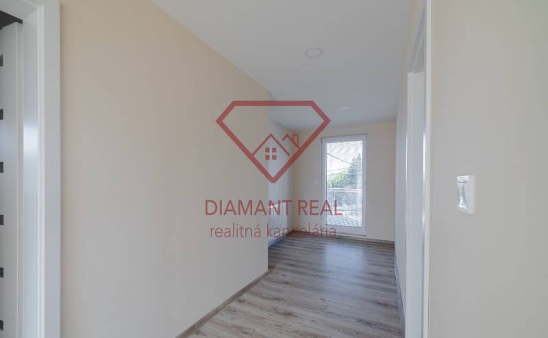 A hallway in a family house with a wooden decor floor and a large window.