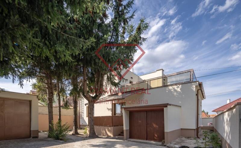 A family house on Trnovecká Street in Trnovec nad Váhom with a built-in garage and tall trees.