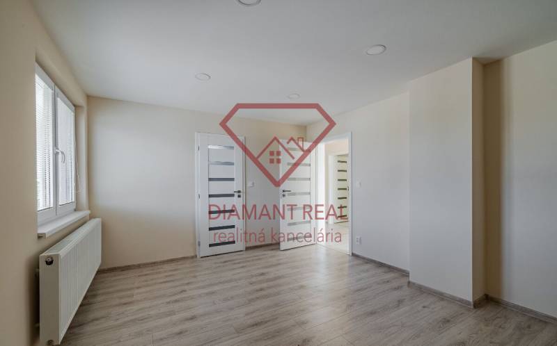 A room in a family house with a wooden decor floor, light walls, and a window.