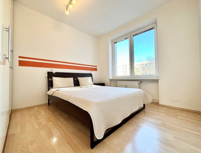 Bedroom with a large bed, white walls, and a floor with a wood decor.