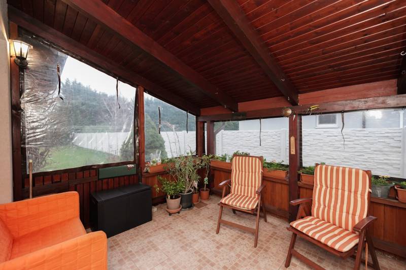 Winter garden of the family house with chairs and plants, tiled floor.