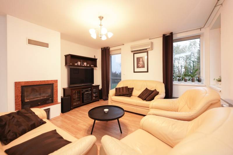 Living room in a family house with a fireplace, leather sofas, and a floor with a wood decor.