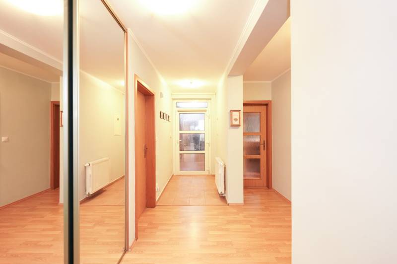 Interior of a family house with a wooden decor floor, a mirror, and wooden doors.