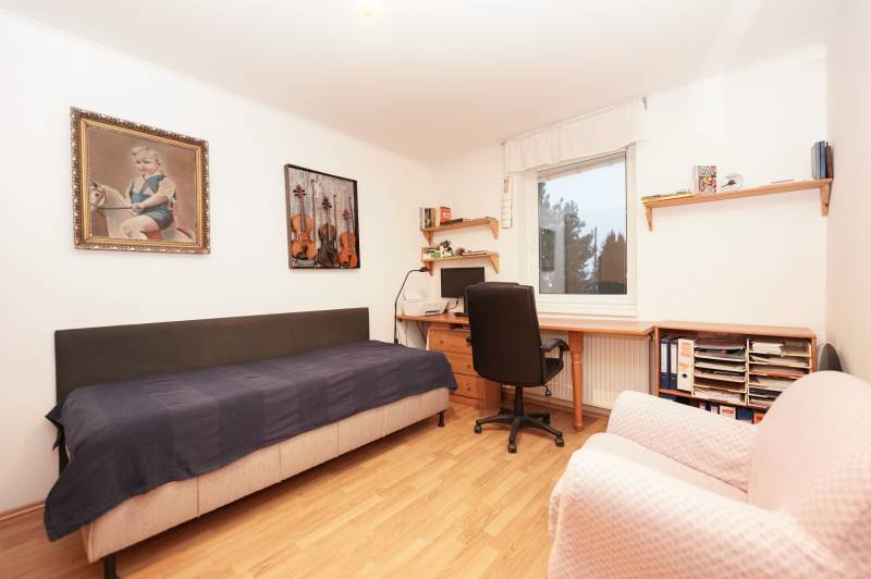 A children's room in a family house with a bed, a desk, and pictures on the walls.