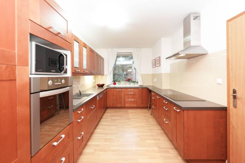 A kitchen in a family house with a wooden decor, with a cooktop and a microwave oven.