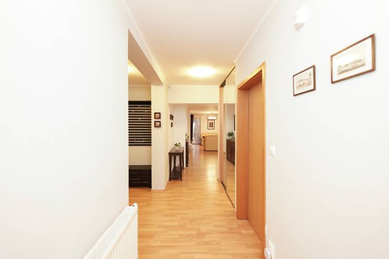 A hallway with a wooden decor floor in a family house, with a coat rack and a radiator.