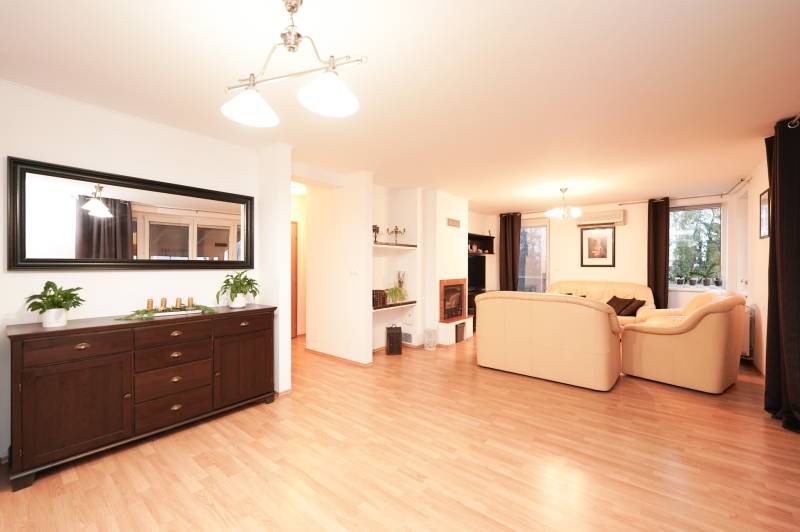 Living room with a fireplace and light furniture, wooden decor flooring, family house.