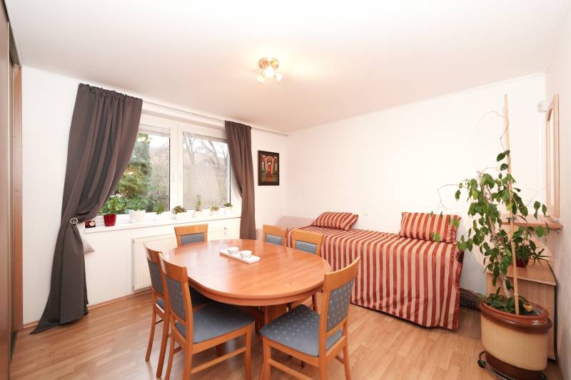 Dining room in a family house with a round table, chairs, a sofa, and a floor with a wooden decor.