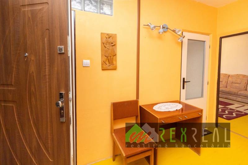 Interior of a 4-room apartment with orange walls, wooden furniture, and ornamental carvings.