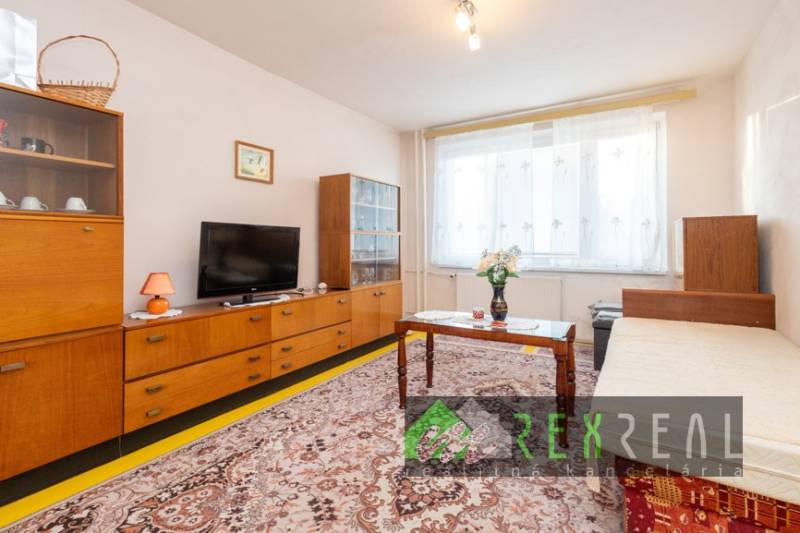 Living room in a 4-room apartment with older furniture and a wooden decor floor.