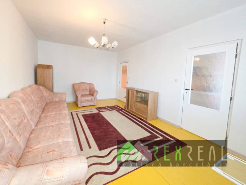 A living room in a four-room apartment with carpet decor and simple furniture.