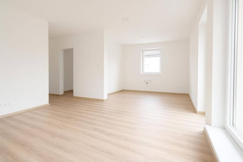 White interior of a family house with a wood-patterned floor and a large window.