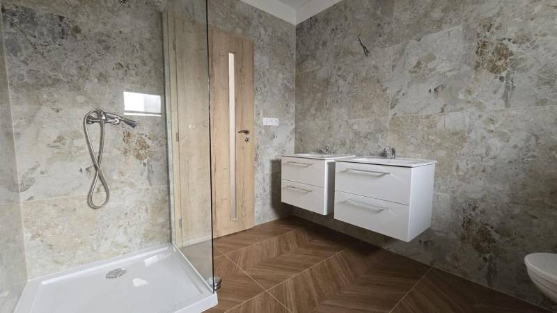 A bathroom in a family house with stone cladding and a shower enclosure.