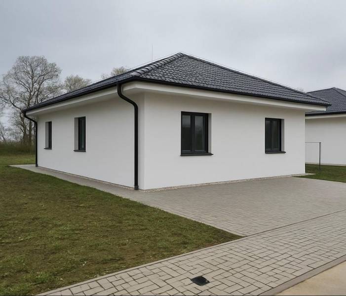 A family house in Cífer with a sloped roof and a paved walkway.