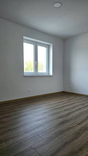 A room in a family house with a wooden decor floor and white walls.
