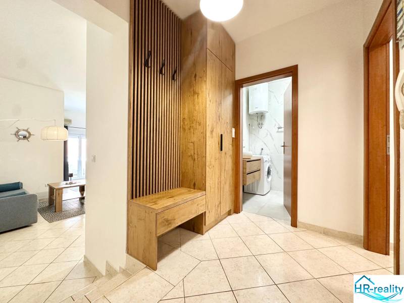 The hallway of a recreational apartment with a washing machine and a coat rack with a wooden decor.
