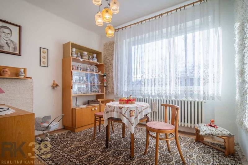 Dining room in a family house with carpet, wooden furniture, and decorations on the shelves.