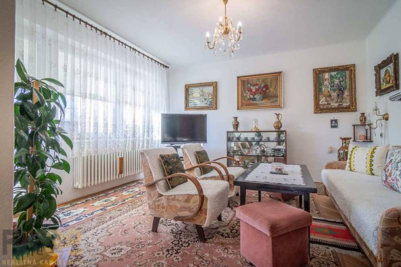 Living room in a family house with a sofa, TV, and paintings on the walls.