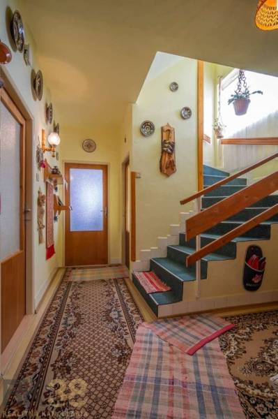 Interior of a family house with carpet, wall decorations, and a wooden staircase.