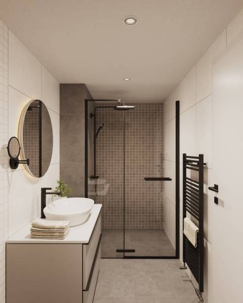 A bathroom in a building with a glass shower enclosure and a white sink.