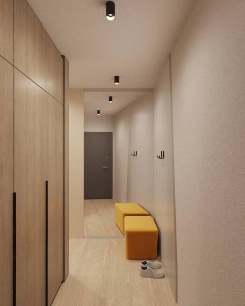 Interior of a building with wood-patterned flooring, wardrobe, mirror, and yellow seating.