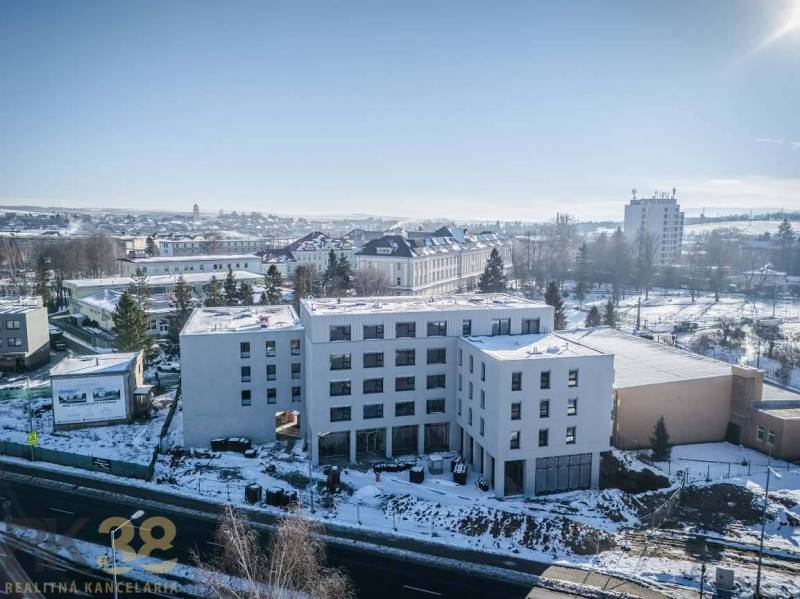 A building in the city of Poprad surrounded by a snowy landscape and other structures.