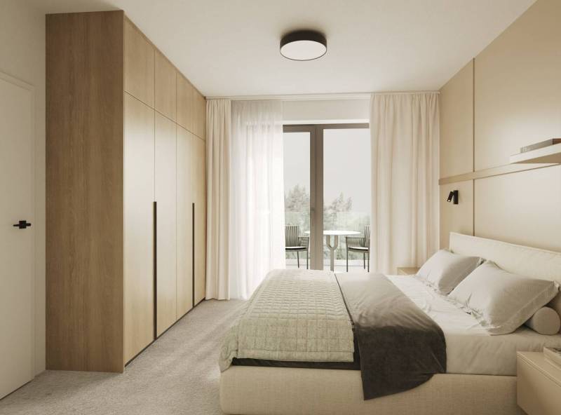Bright bedroom with a bed, built-in wardrobe, and a view of the balcony through glass doors.
