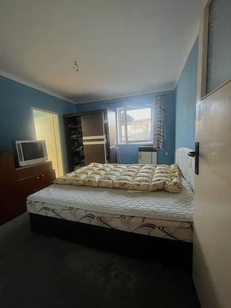 Bedroom with a bed, dark wardrobe, television, and blue walls in a family house.