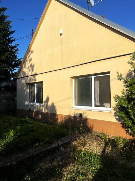 A family house in Diakovce with a sloped roof and yellow facade, surrounded by greenery.