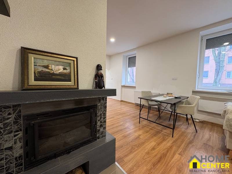Fireplace and dining table in a studio apartment with wood-patterned flooring.