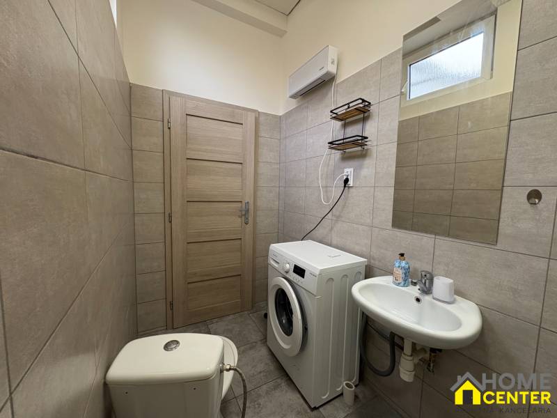 Bathroom with a washing machine and a sink in a studio apartment with tiling.