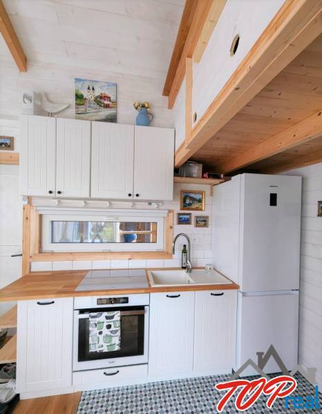 A kitchen in a family house with white cabinets, wooden decor, and colorful tiles.