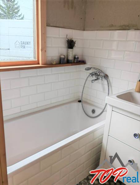 A bathroom in a family house with a built-in bathtub and white tiles.